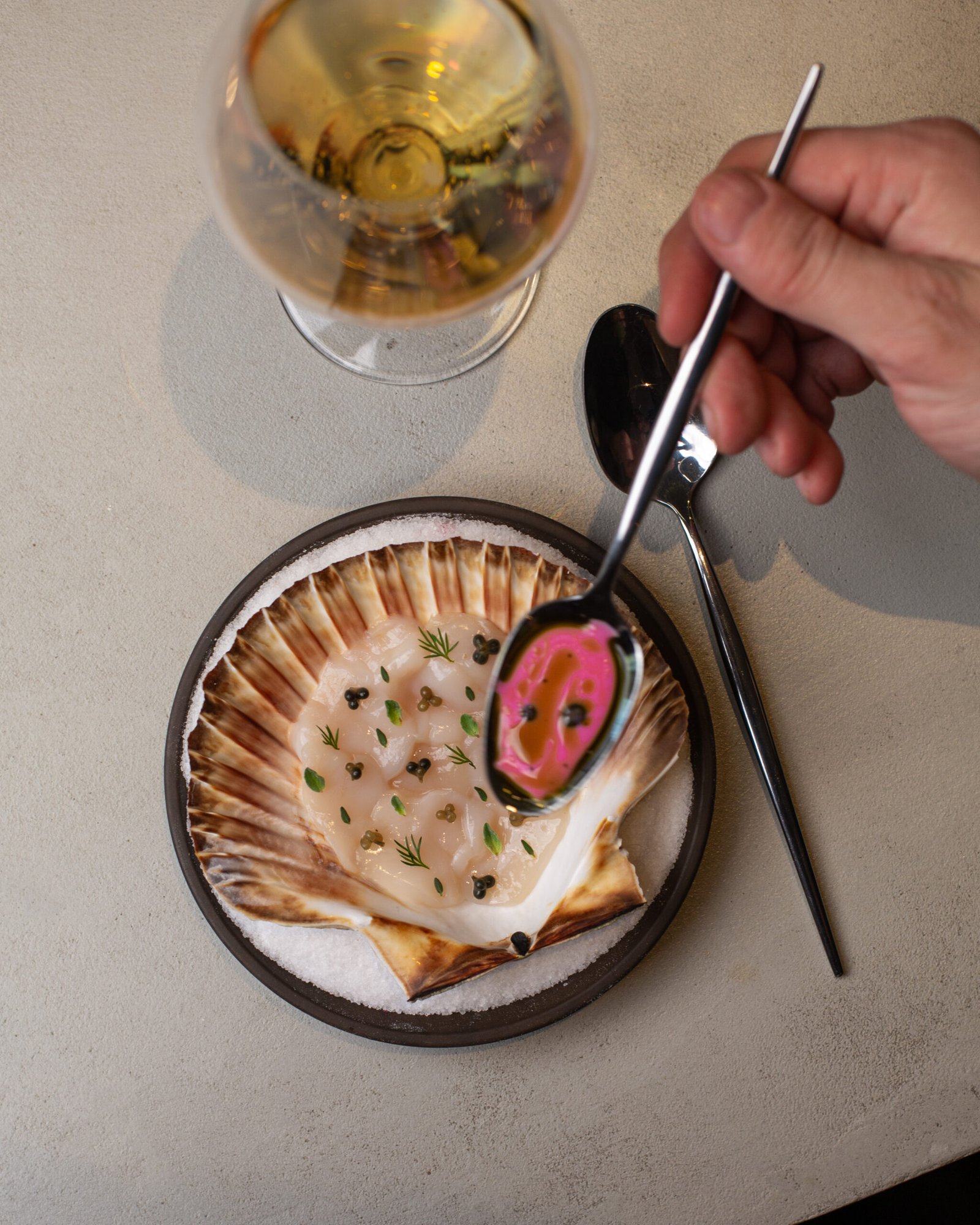 Scallops dressed with a pink sauce at the table